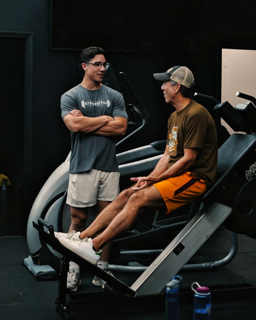 Coach talking through a plan with a client at the leg press