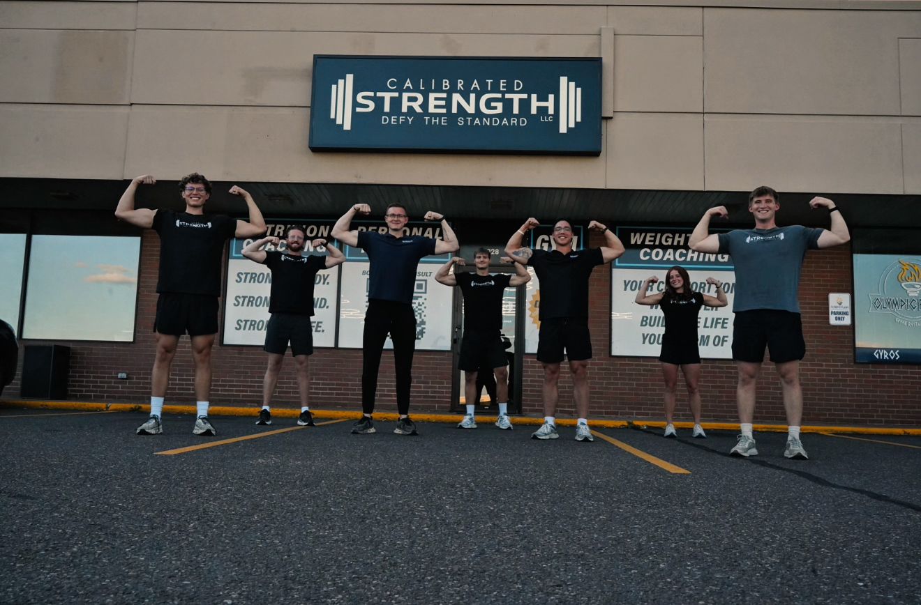 The Calibrated Strength coaching team flexing outside the gym on London Rd.